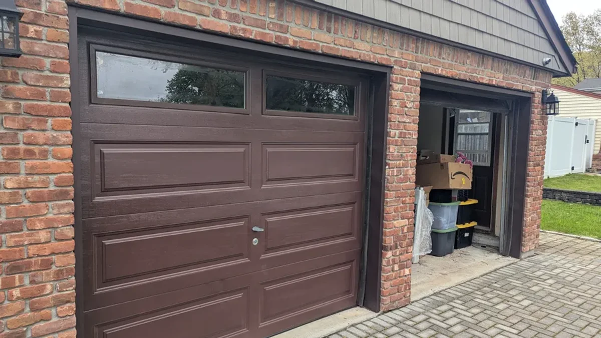 Brown raised-panel garage doors in a brick building