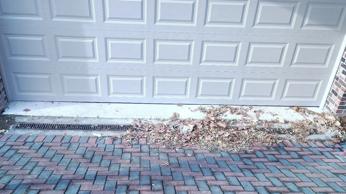 White raised-panel garage door opening onto a paved driveway
