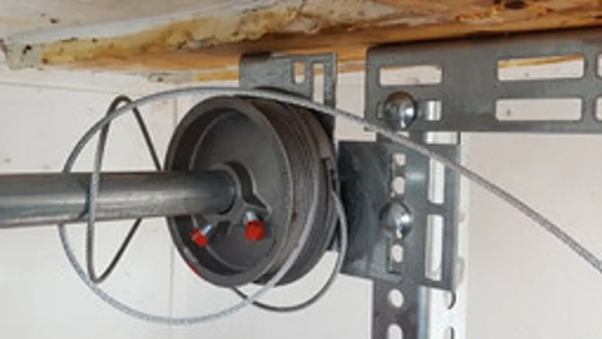 Tangled garage door cable wrapped around a drum