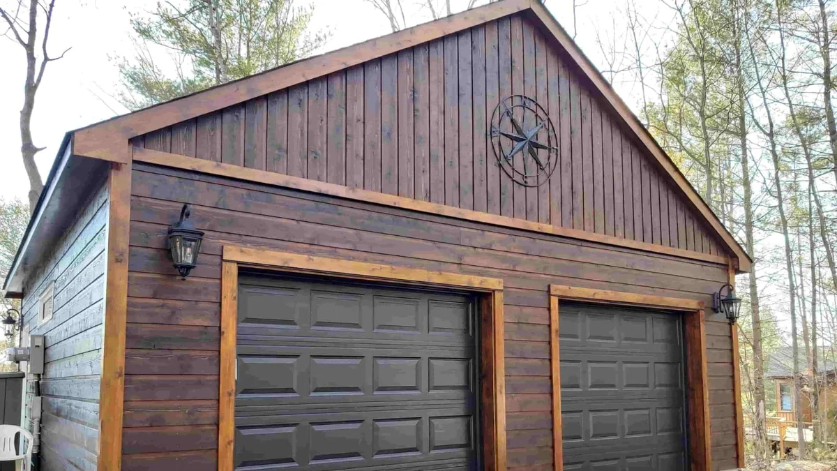 Detached timber garage with two dark sectional doors