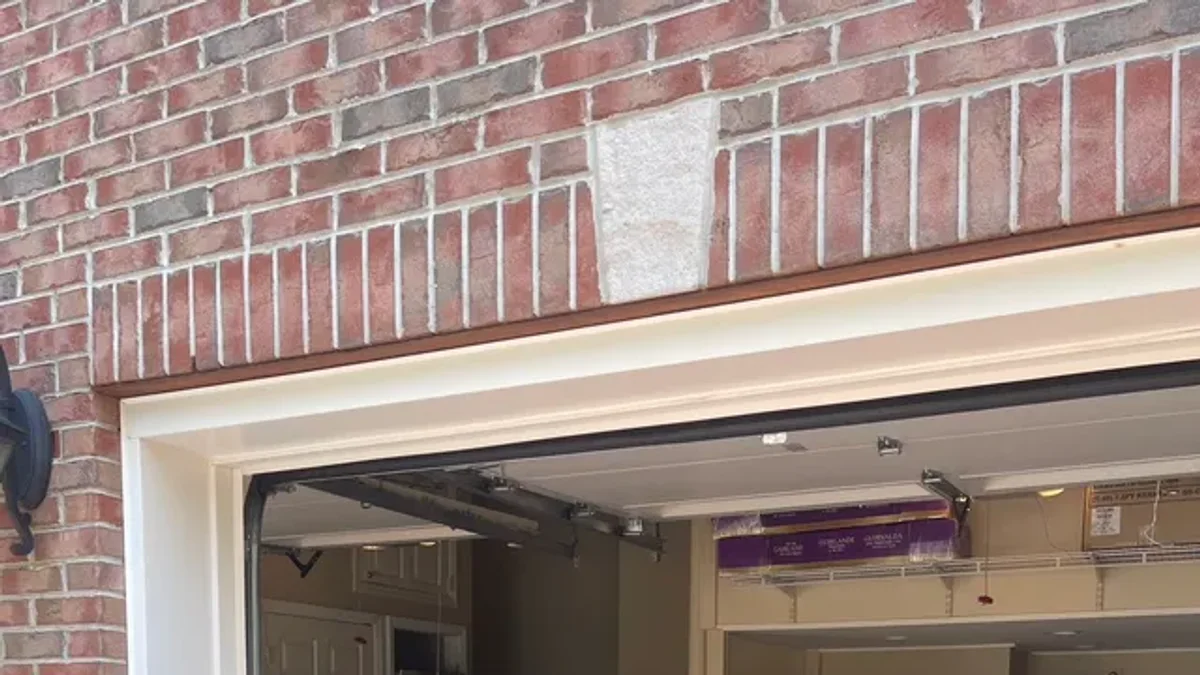 Two technicians working at a brick garage entrance