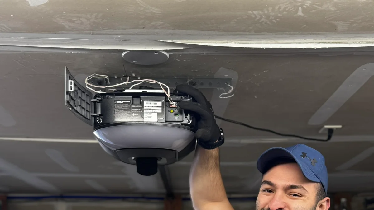Technician inspecting a ceiling-mounted garage door opener