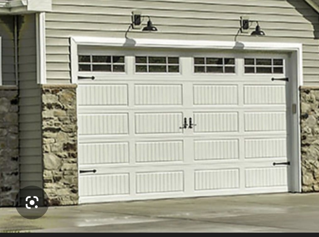 Carriage house garage door installation — white door with decorative windows and hardware on stone home