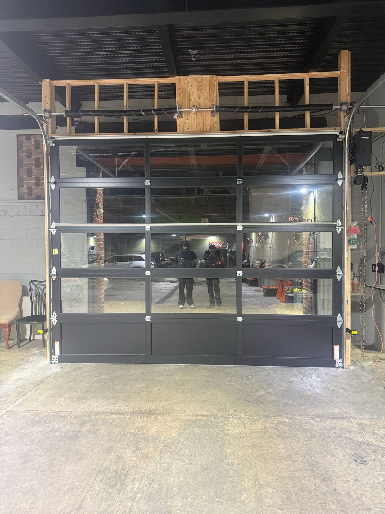 Commercial glass garage door installation — full-view aluminum and glass door at industrial facility
