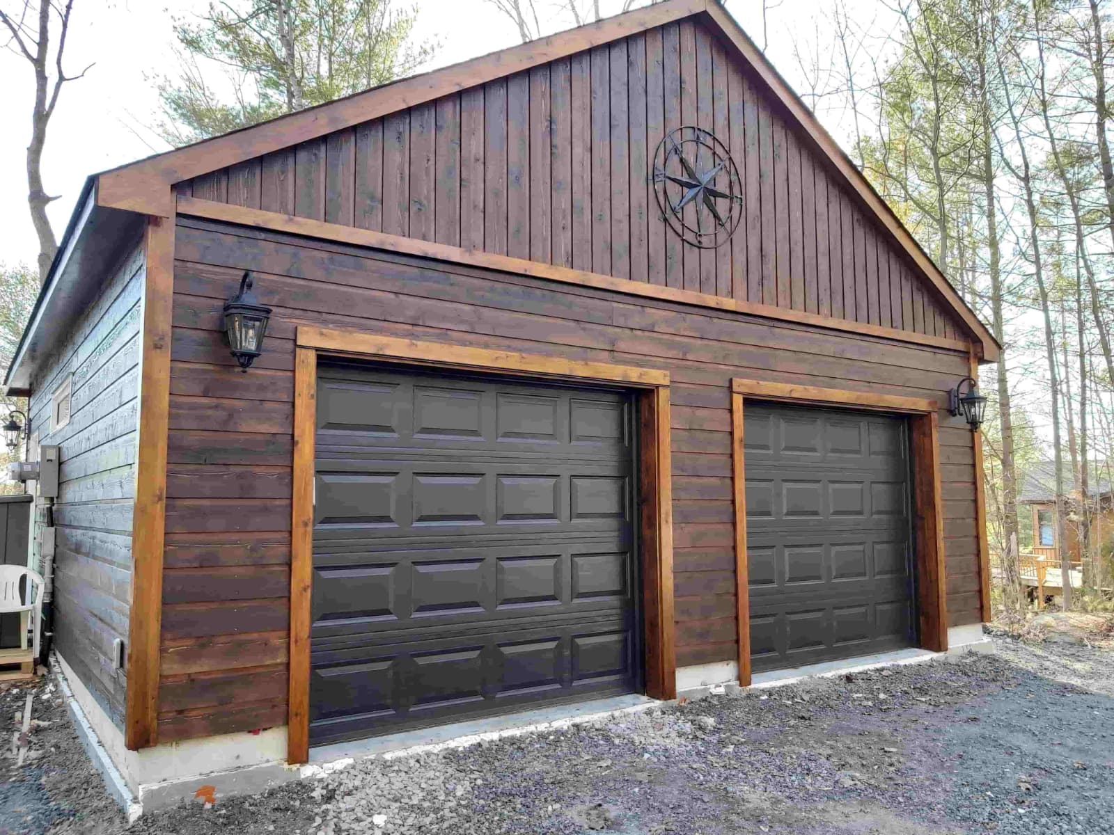 Custom garage door installation — dark sectional doors on rustic wood barn garage