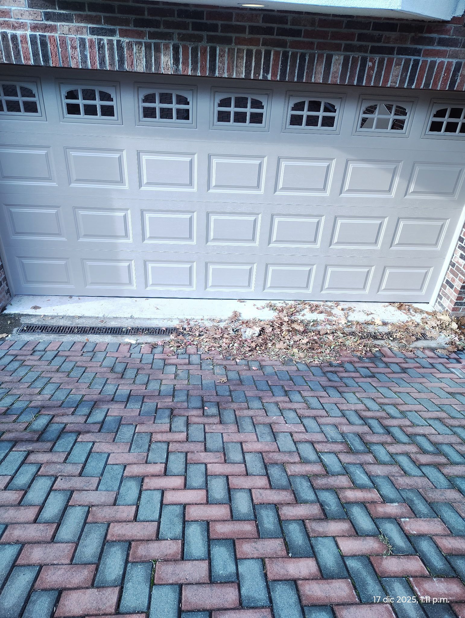 Insulated garage door installation — white raised panel door on brick home