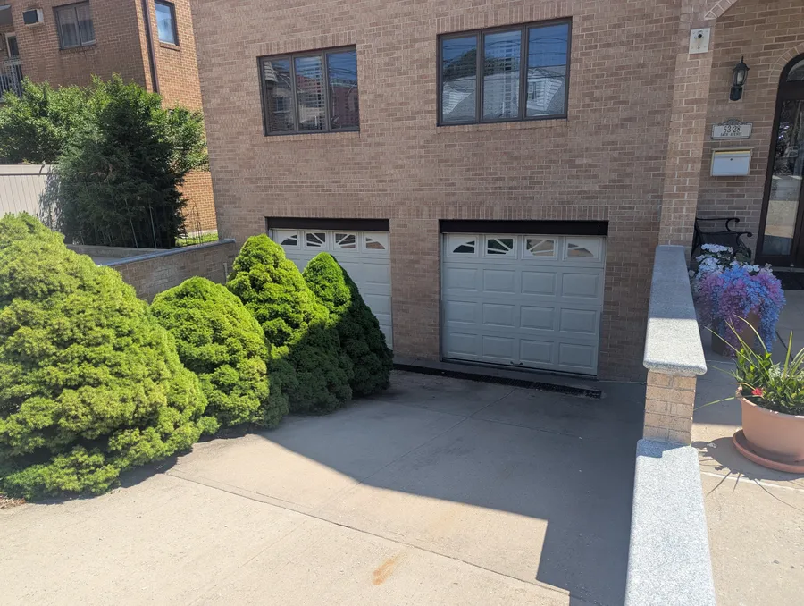 Pair of white garage doors with decorative arched window inserts on a Westchester County, NY home